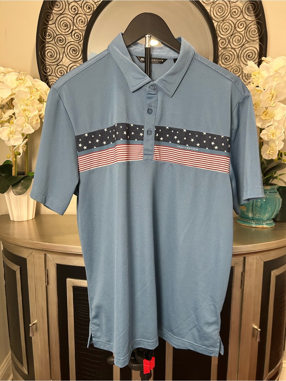 Travis Mathew Light Blue Polo with Stars & Stripes Chest Band
